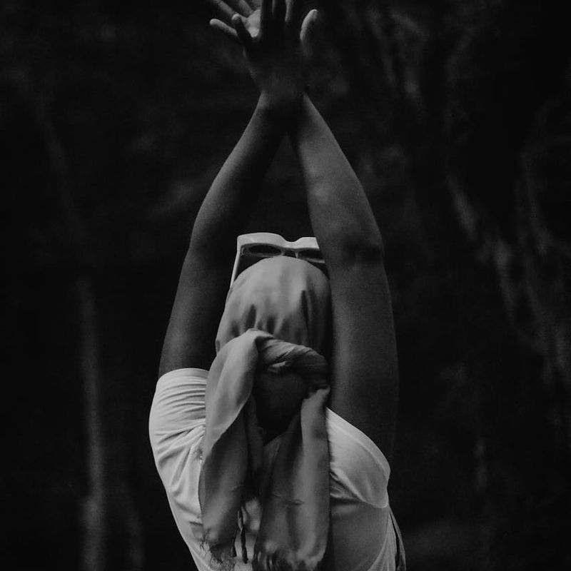 Person in a balanced yoga pose against a dark background.